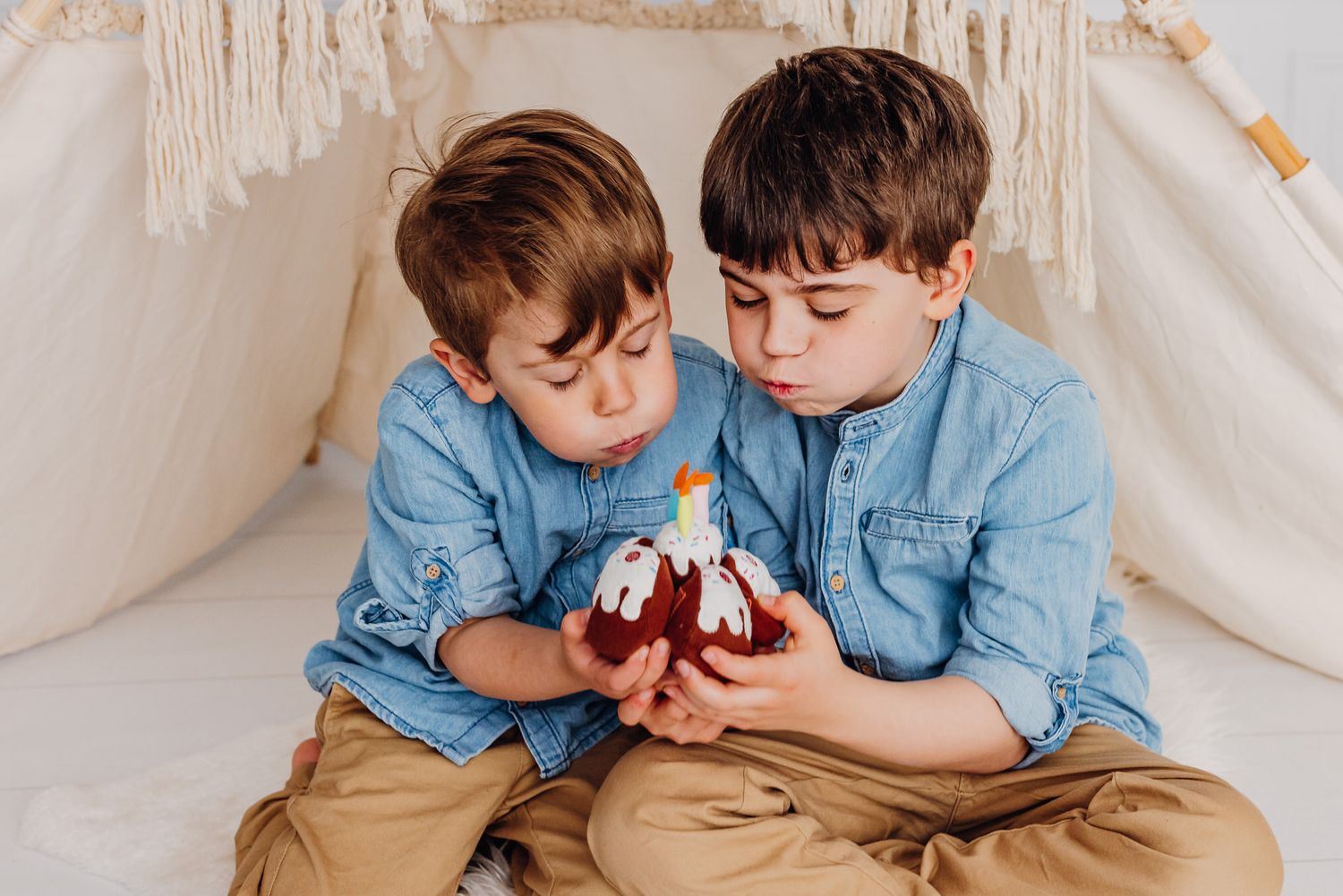Zwei kleine Jungen in passenden Jeanshemden, die sich gemeinsam etwas ansehen.