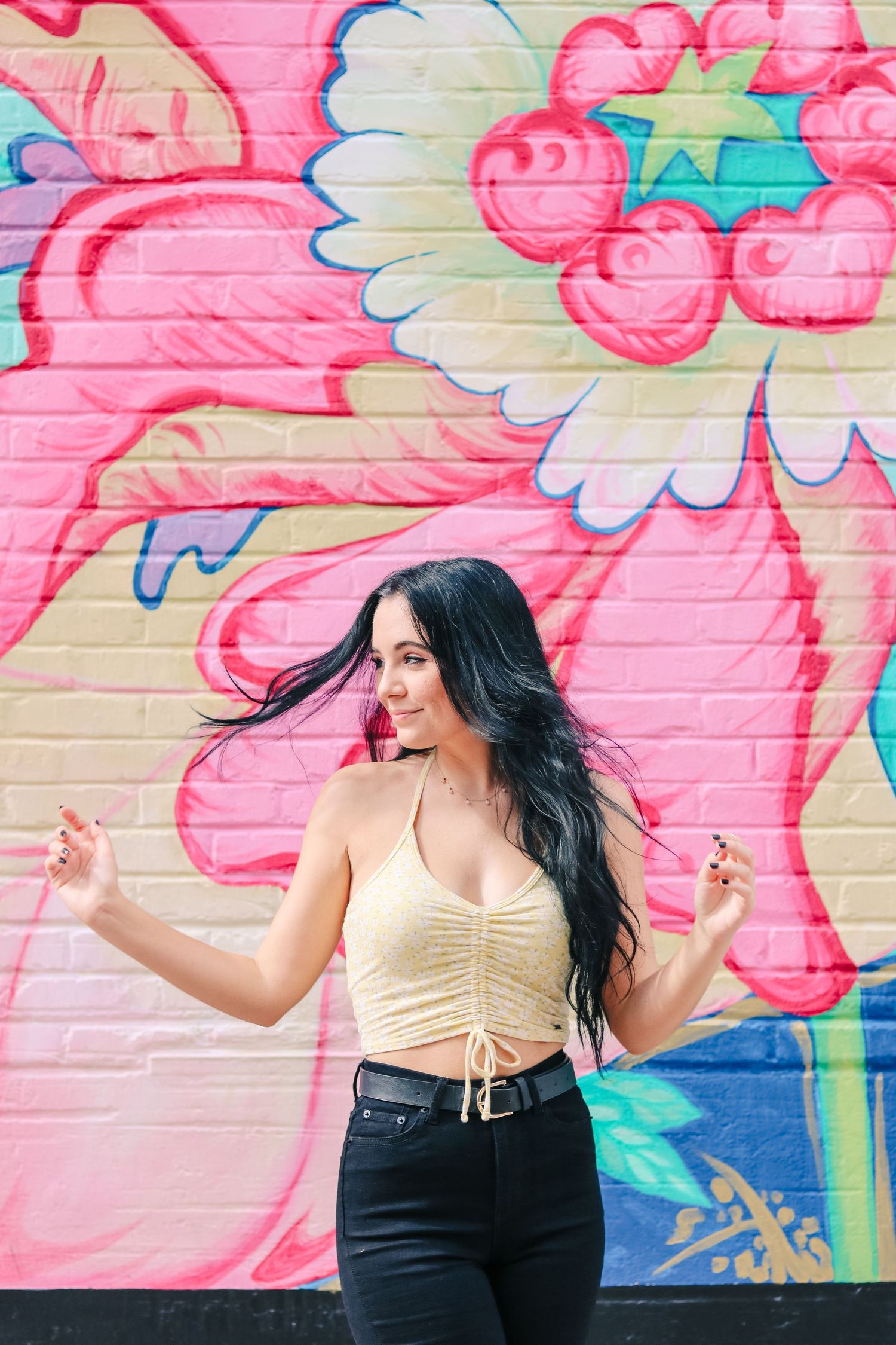 girl with long hair posing in front of a mural