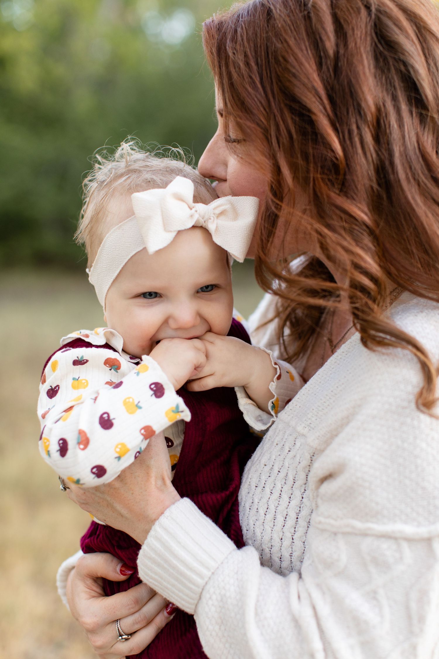 A tender moment between caregiver and baby wearing matching burgundy and white outfits.