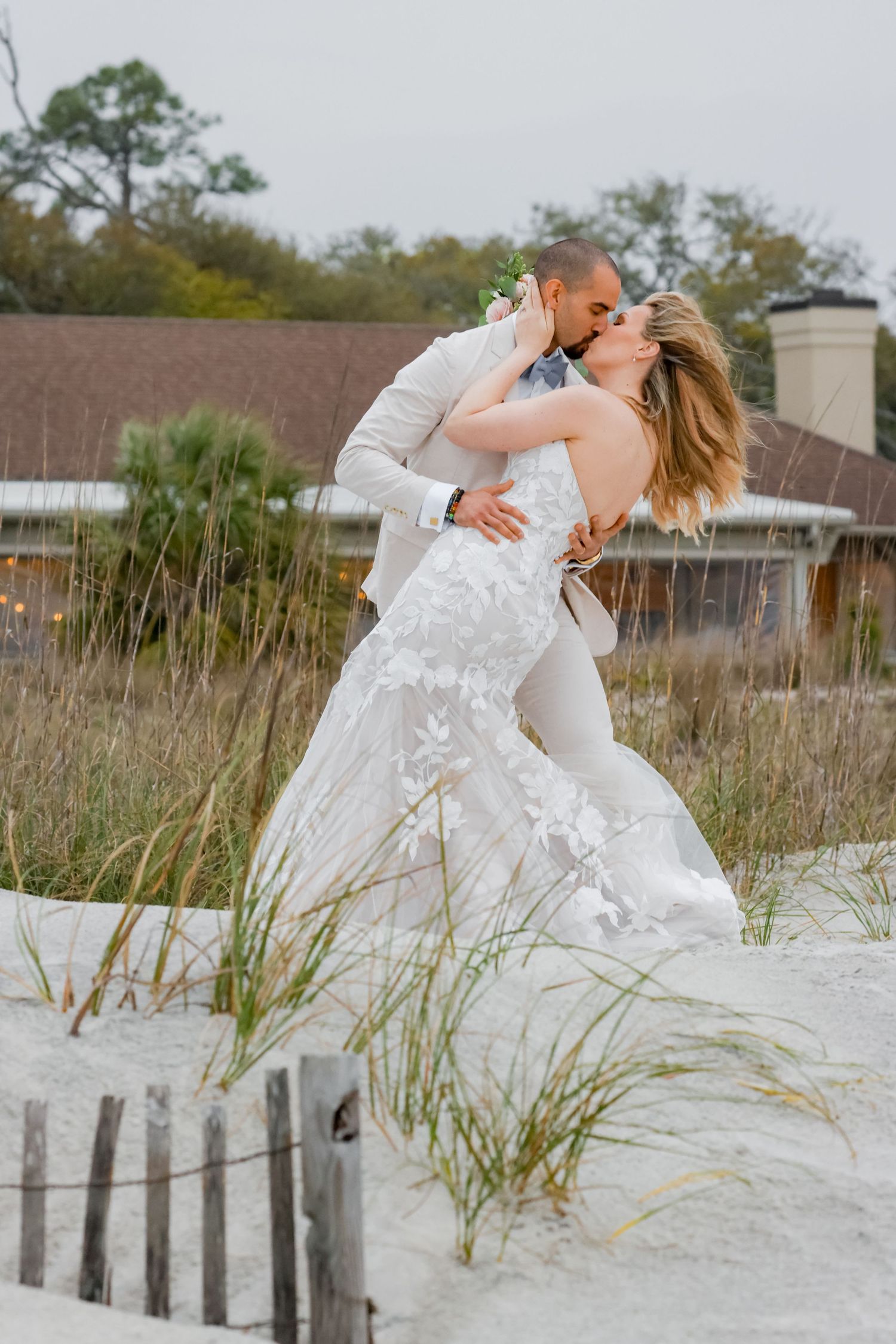 A romantic wedding moment captured in the sand dunes with sea grass swaying.