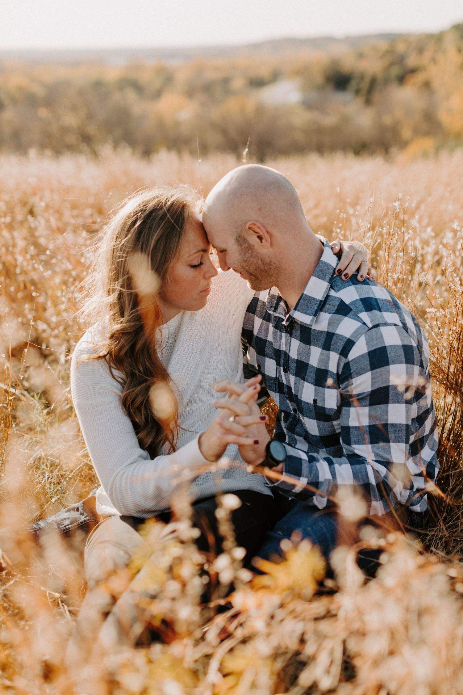 Romantic couple shares intimate moments in sun-drenched autumn field during golden hour.