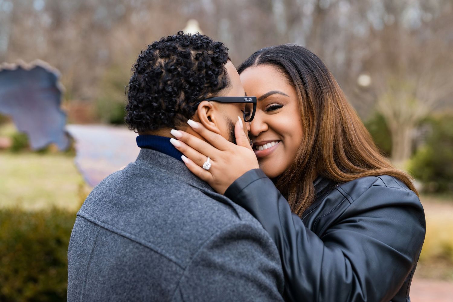 A joyful couple share an intimate moment outdoors while wearing winter coats.