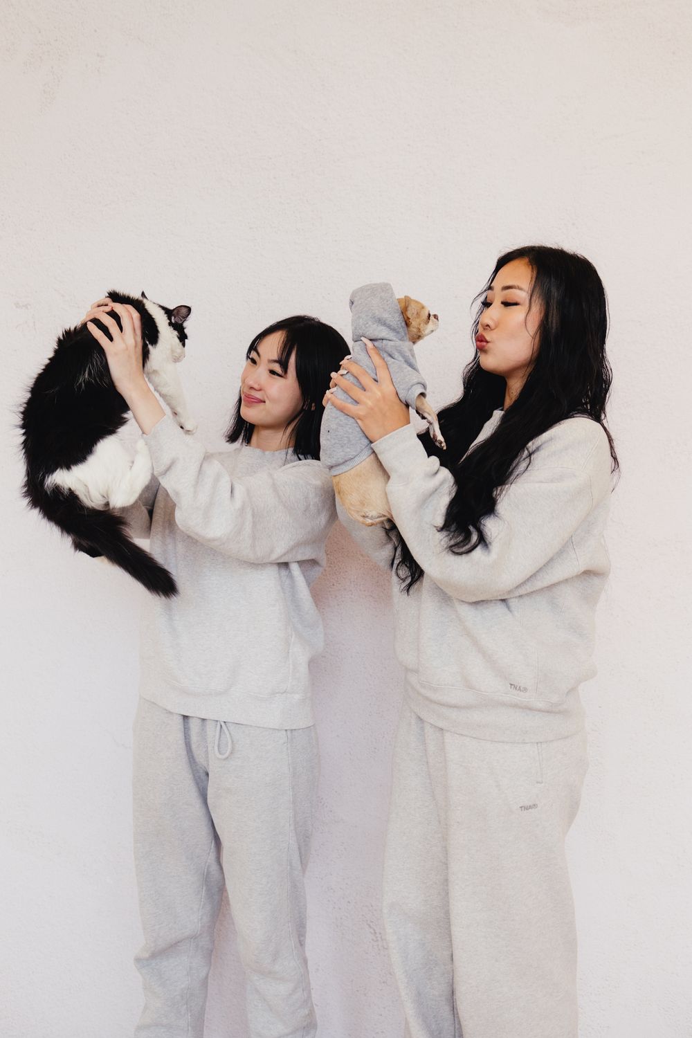 Two people in matching white outfits playfully interacting in a minimalist photo sequence.