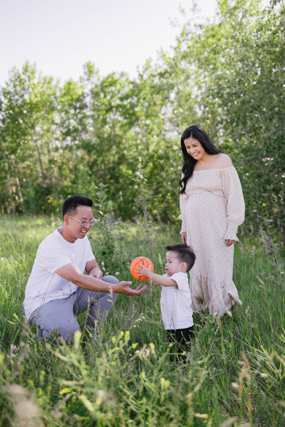Family sharing tender moments together in a sunlit meadow with wildflowers.