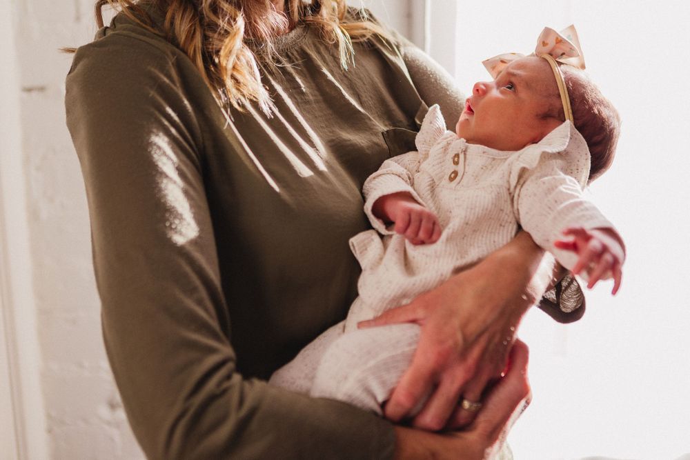 Parent holding and gazing lovingly at newborn baby in soft natural light.