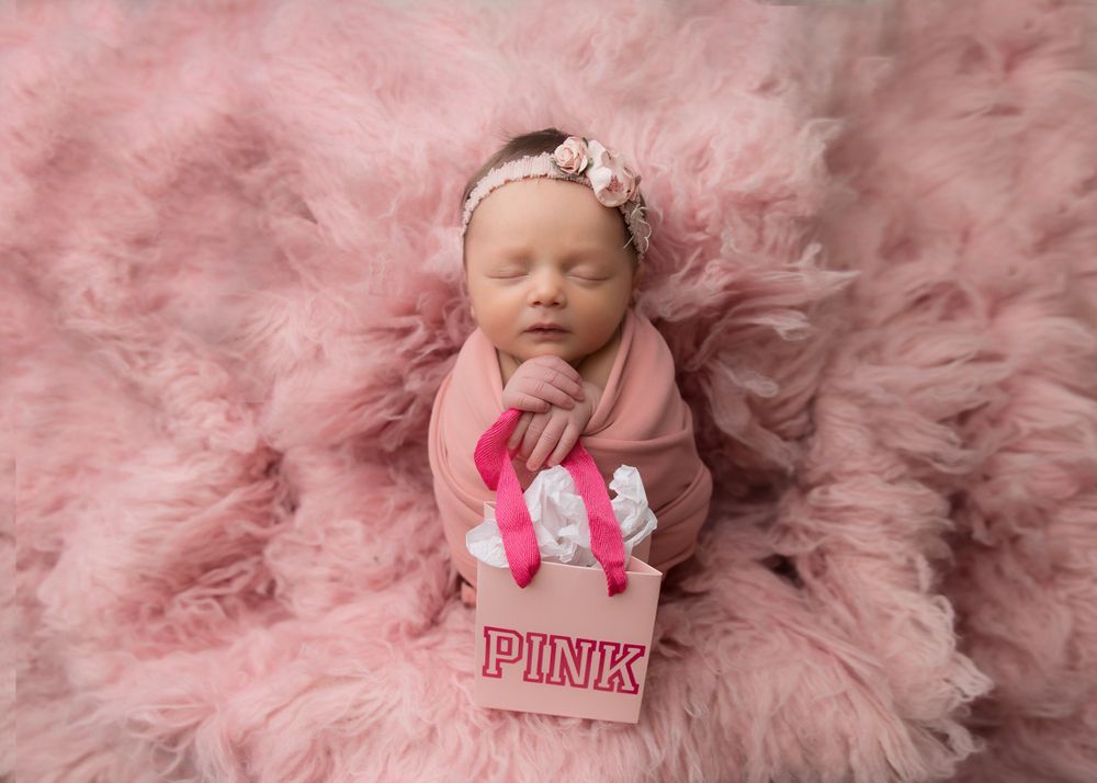 Newborn portrait on pink fluffy backdrop with matching accessories.