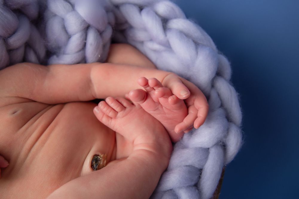 Close-up of tiny baby feet resting on chunky knit blue blanket.