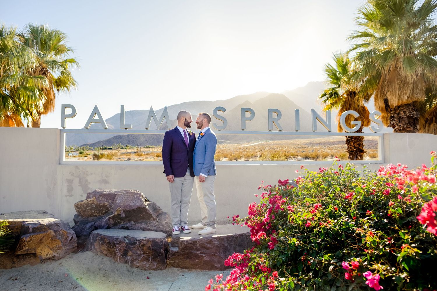 Palm Springs resort entrance with palm trees and flowering gardens.