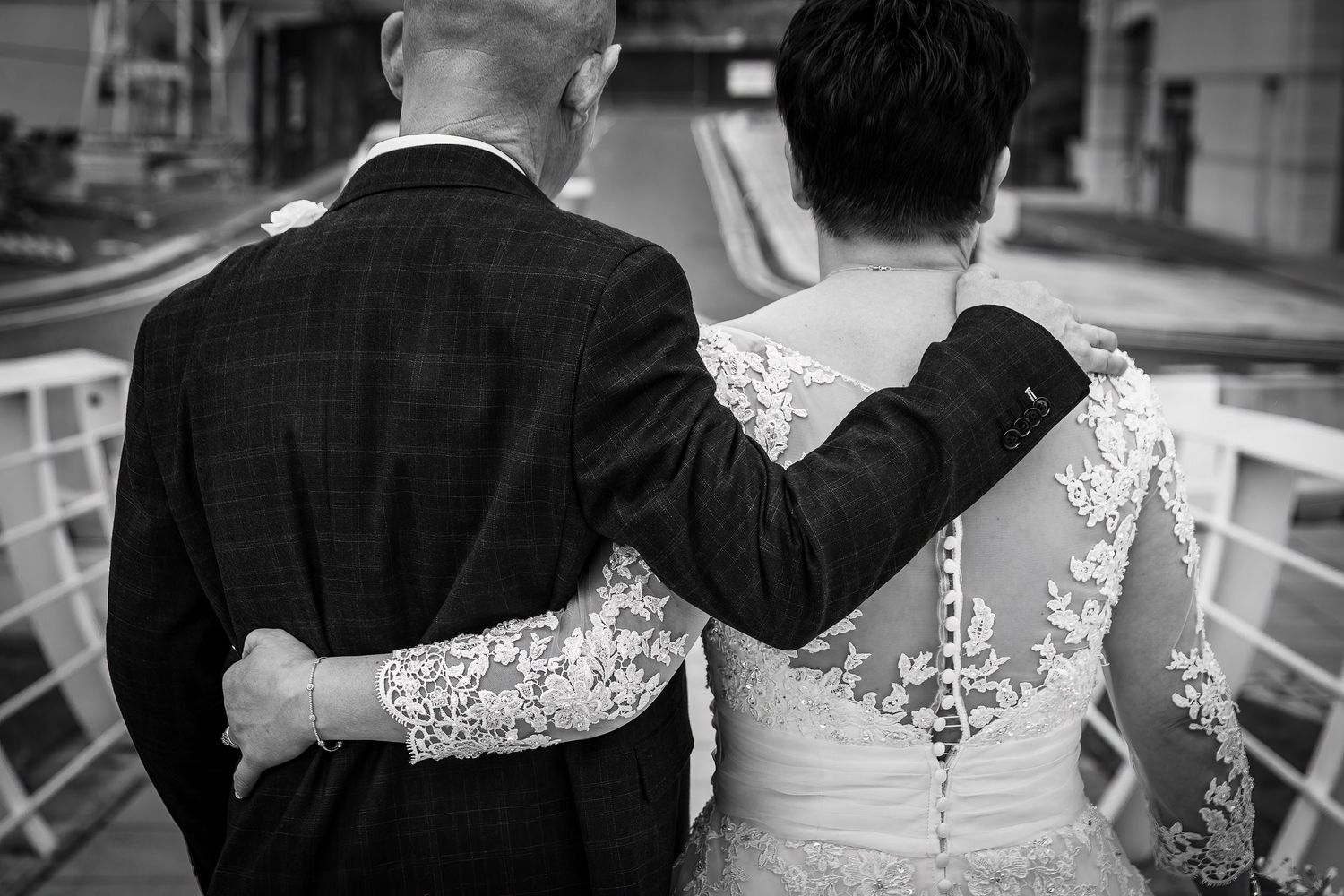 Bride and groom taken from behind, Grooms hand on her shoulder, hers around his back. Liverpool wedding photographer.