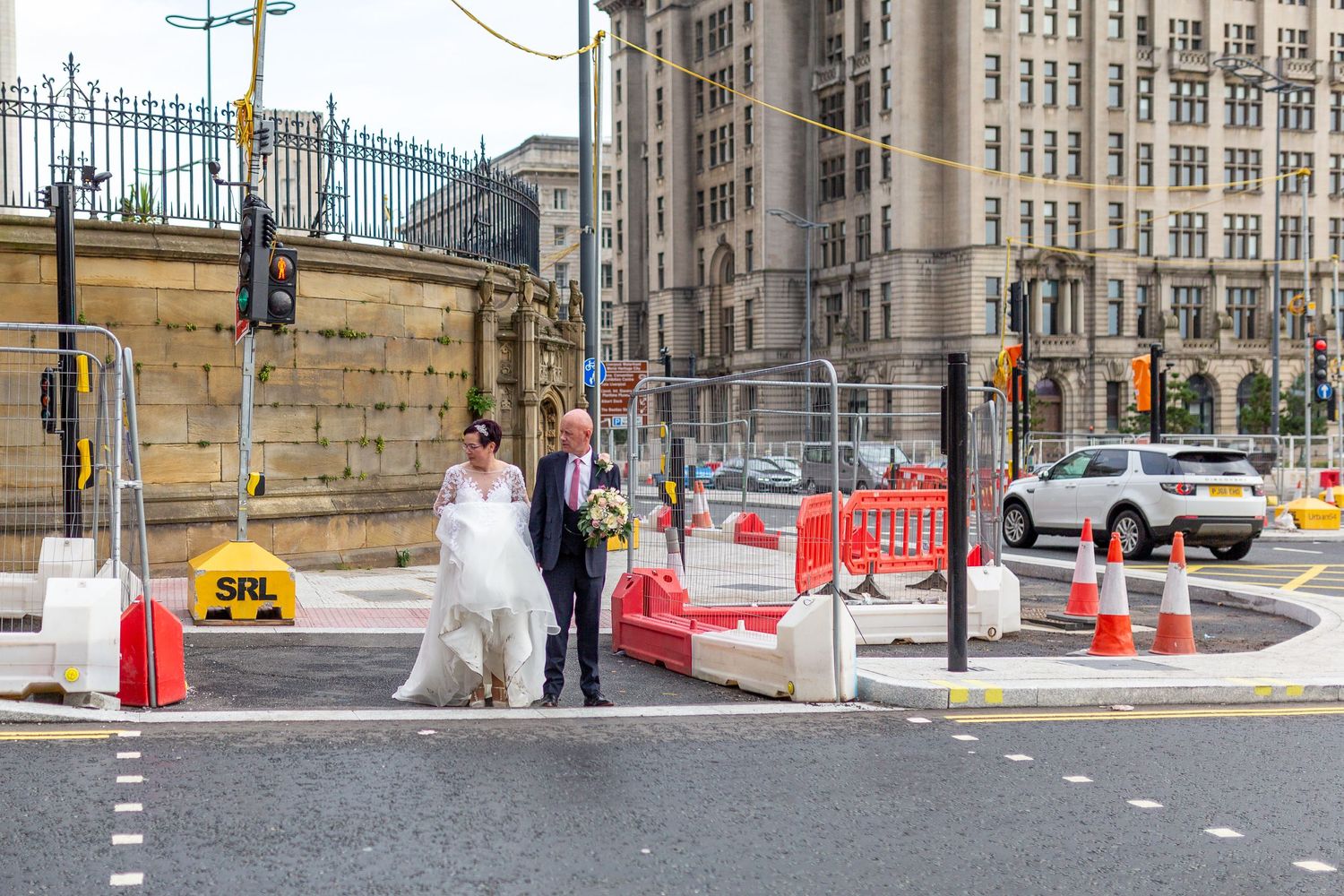 Bride and groom cross the busy dock road surrounded by roadworks Liverpool city centre. Stuart Morris Photography