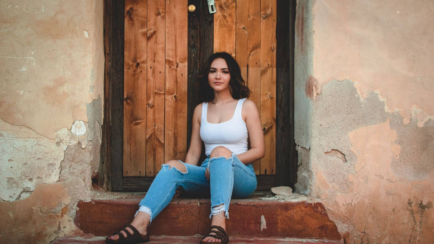 Rustic portrait session featuring wooden doors and weathered wall textures.