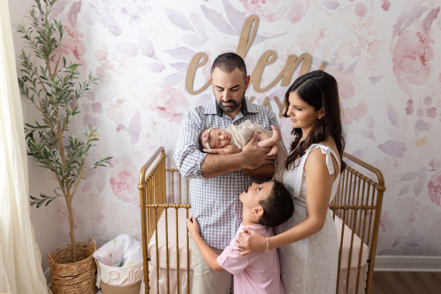 Family moment in nursery with gold decor and floral wallpaper background.