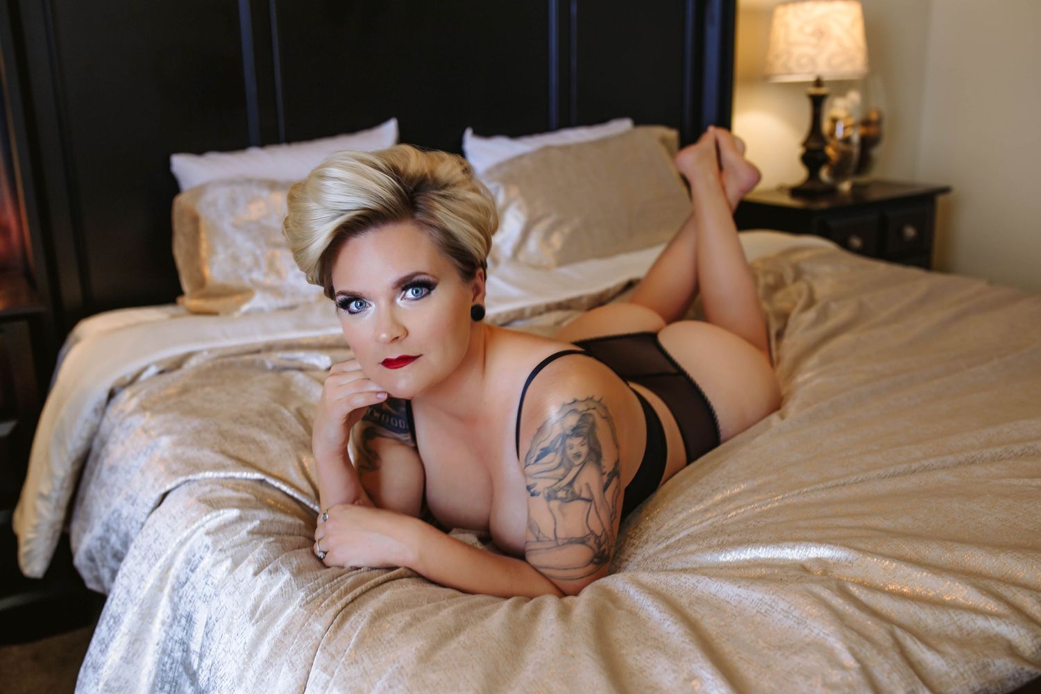 Blonde bombshell, seductively laying in a shimmery gold bed for intimate photos