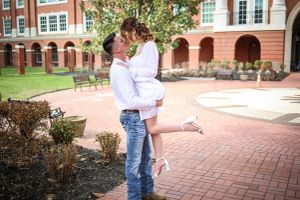 Romantic couple embrace on brick courtyard path near historic building.