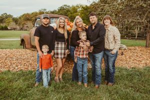 Extended family group photo in casual attire against rustic fall backdrop with vintage truck.