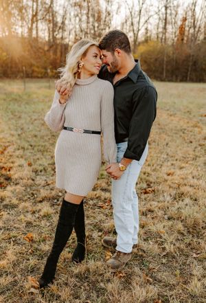 Romantic couple embracing in autumn field during golden hour sunset.