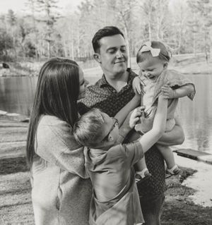 Happy family enjoying a moment together by a lake with trees in the background.