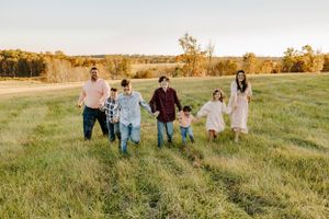Family walking together across a green field during golden hour.