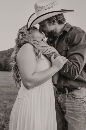 Black and white portrait of couple embracing in rustic country setting.