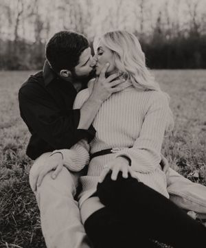 Intimate black and white portrait of couple sharing tender moment in field.