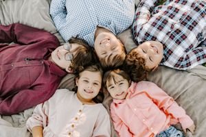 Playful overhead shot of children lying in a circle with their heads together.