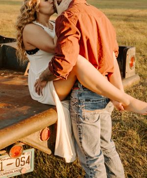 Romantic couple embracing against rural vintage truck at sunset.
