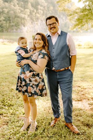 Family portrait taken outdoors in warm sunlight with floral dress and formal attire.
