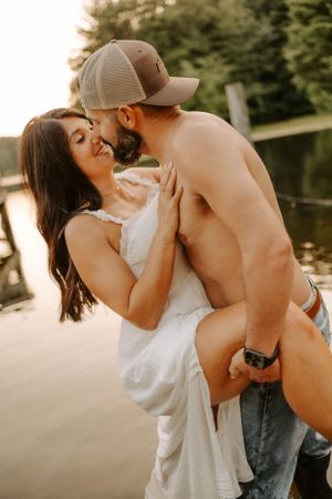A romantic moment captured at sunset by the lake with warm golden lighting.