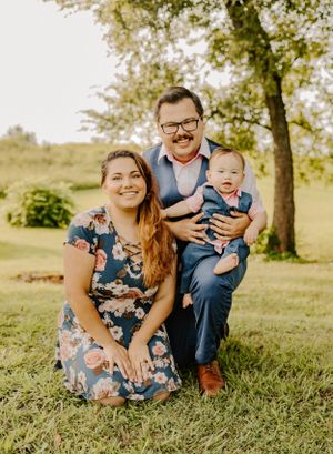 Joyful family sitting together on grass during autumn photo session.