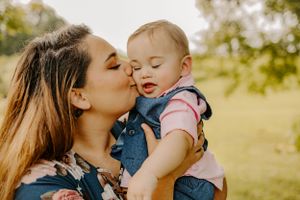 Tender moment between parent and baby outdoors in natural lighting.