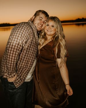 Romantic sunset silhouettes couple by tranquil lake at golden hour.