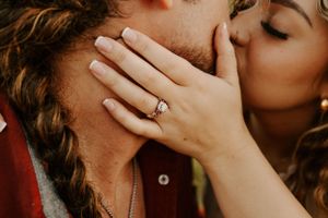 Close-up of engagement ring visible during intimate moment between couple.