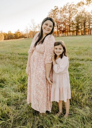 Sweet outdoor portrait in a grassy field wearing matching floral dresses.