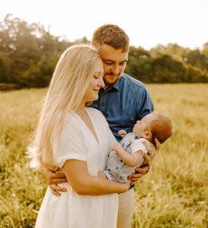 A family moment in a golden meadow during sunset with a small baby.