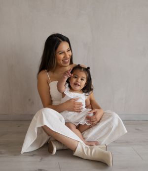 Tender family moments captured in white dresses against a light grey studio setting.