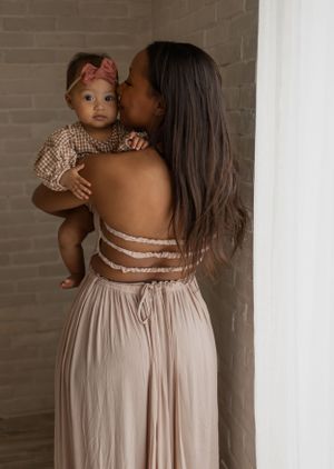 Intimate family portraits featuring beige dress and exposed brick wall details.