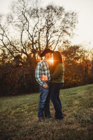 Sunset photography session in rustic field with trees silhouetted against evening sky.