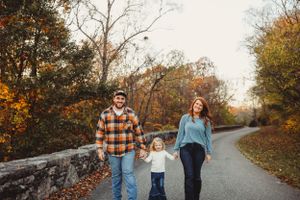 Family walking together on autumn path surrounded by fall foliage.
