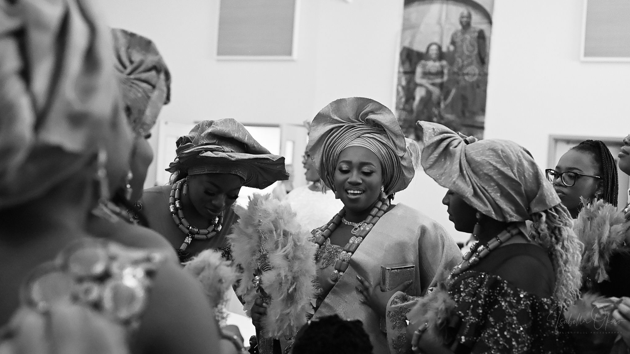 Black and white photo of traditional Nigerian wedding celebration with guests in head wraps.