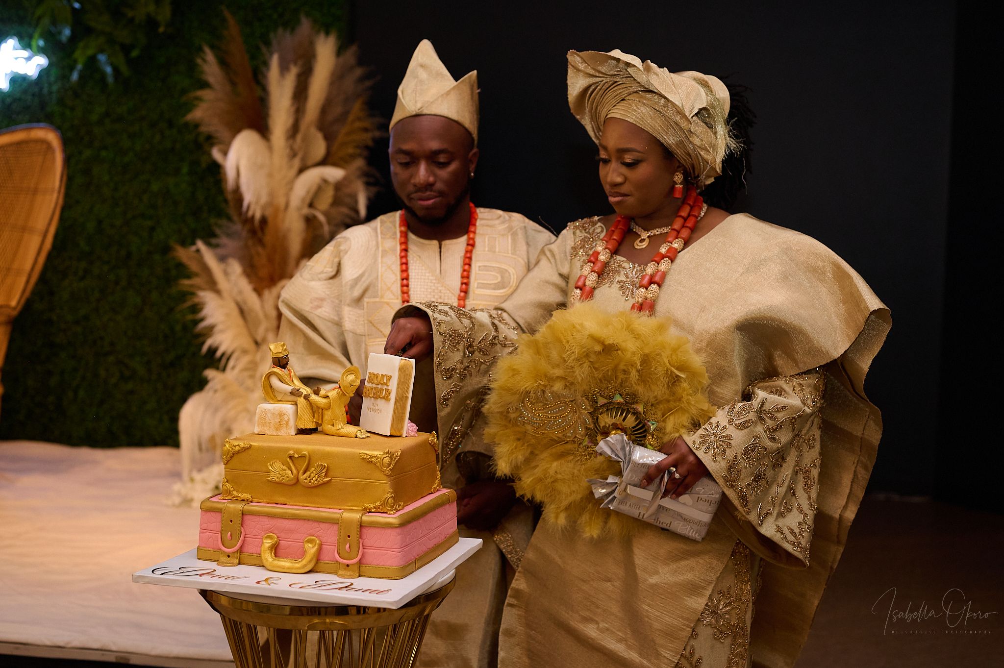 Traditional Nigerian wedding celebration with gold cake and pampas grass decorations.