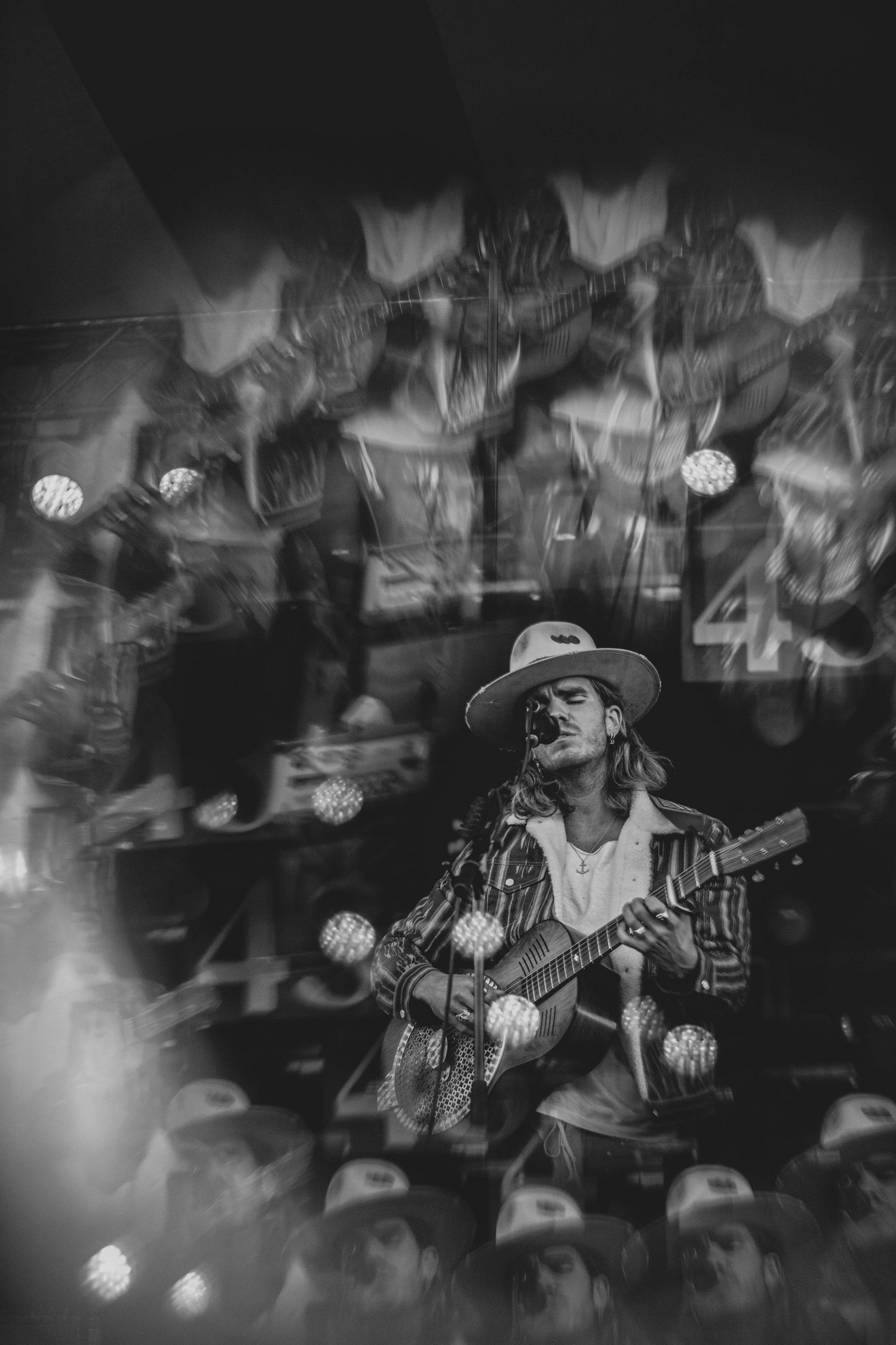 Black and white multiple exposure of musician performing with guitar on stage.
