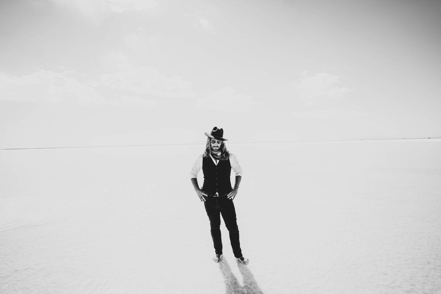 Black and white image of figure standing alone in minimalist snowy landscape.