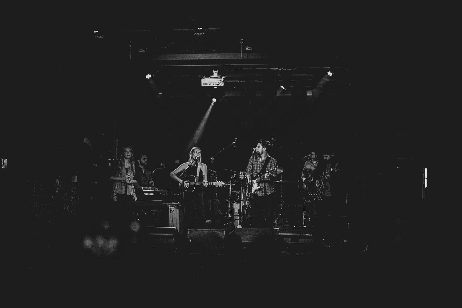 Band performing on stage in black and white with dramatic stage lighting.