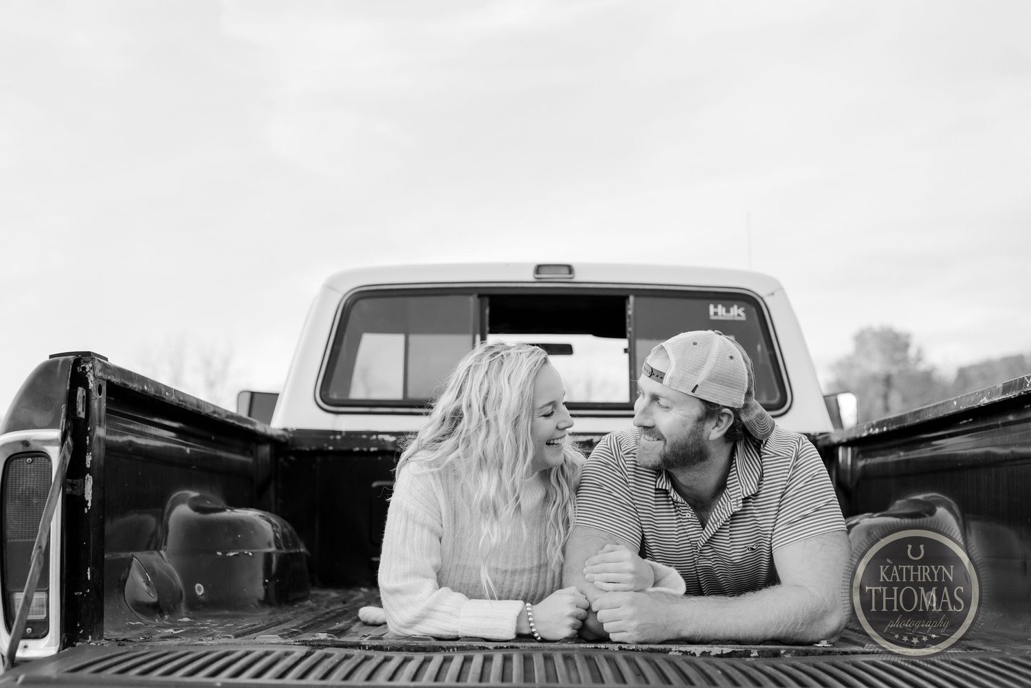 Black and white photo of couple in truck bed during countryside photoshoot.