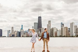Engagement photo of a couple holding hands in North Avenue Beach Chicago with the skyline behind them.