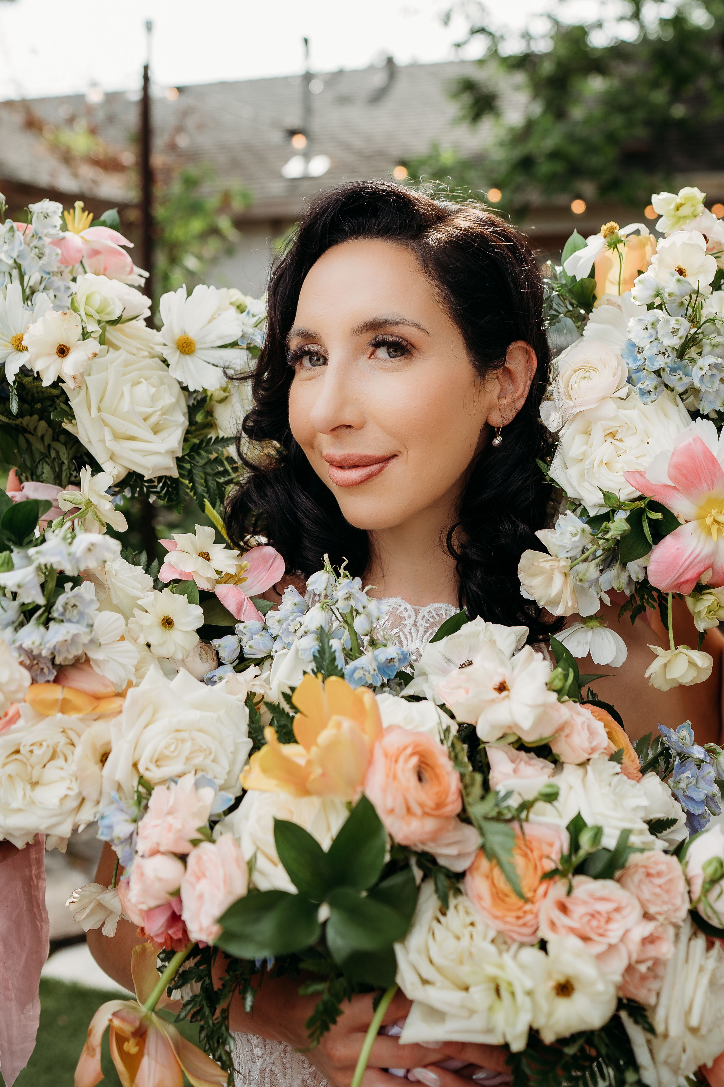 Close up portrait surrounded by luxurious arrangement of roses and mixed flowers.
