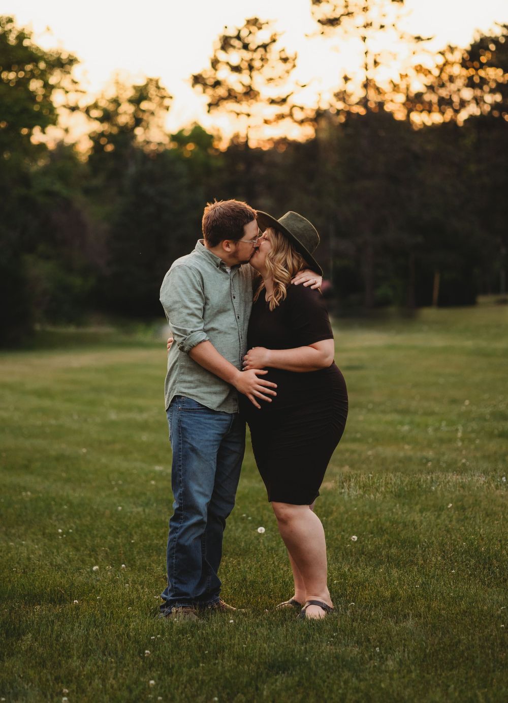 Sweet family interaction photographed in open field during sunset golden hour.