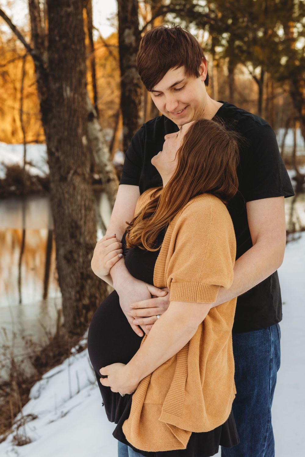 Winter engagement session with couple in casual attire against snowy landscape.
