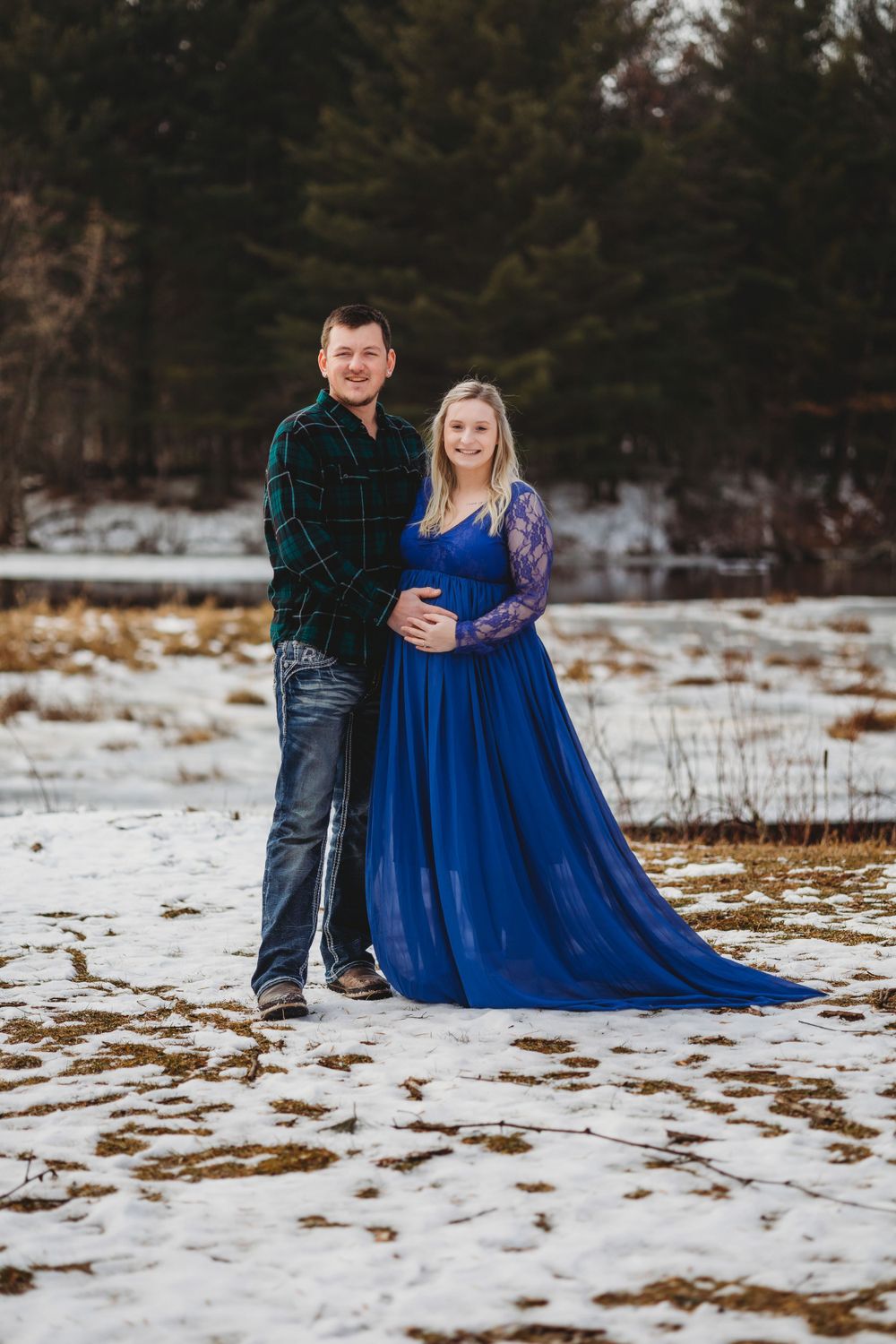 A winter photo session featuring a couple in the snow with a flowing blue dress.