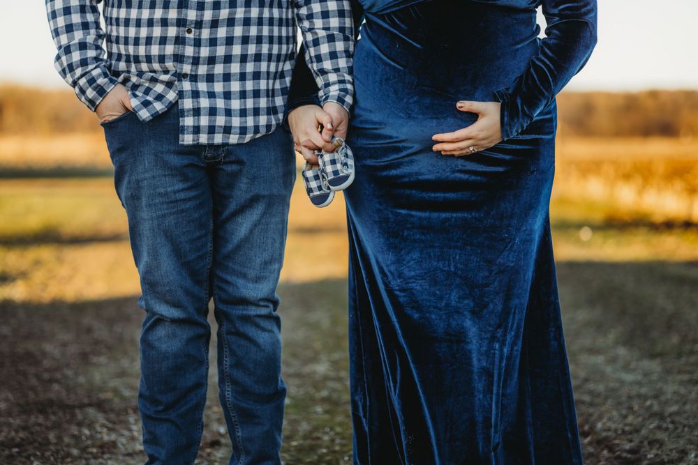 A couple embraces in a field wearing coordinating blue outfits during a photo session.